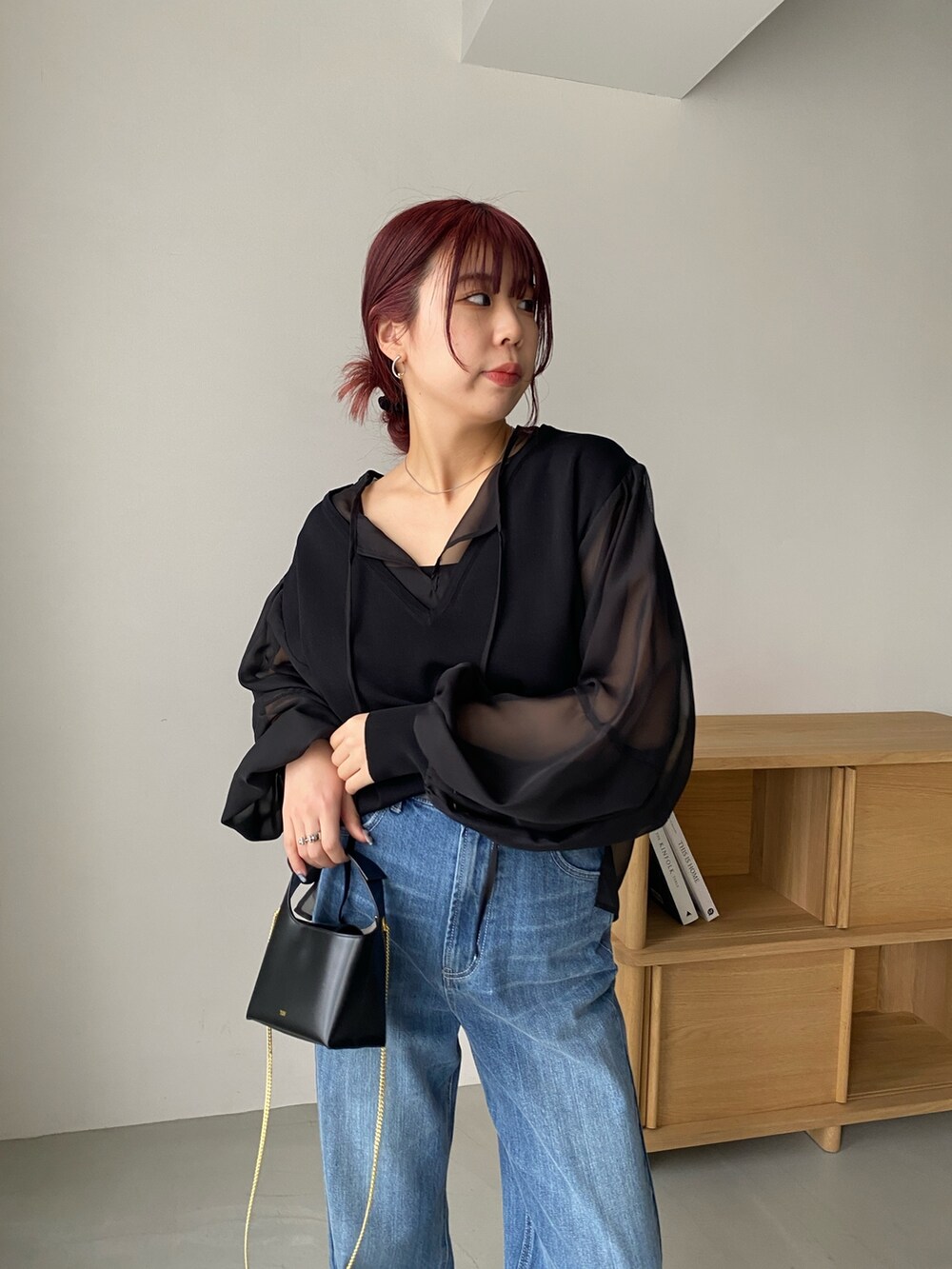 ブラック系のトップス、ブルー系のデニムパンツ、ホワイト系のパンプスを着用したレディースの冬コーディネートの4枚目の写真