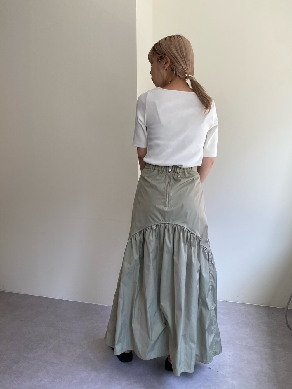 ブラック系のTシャツ/カットソー、グリーン系のスカート、シルバー系のパンプスを着用したレディースの春コーディネートの4枚目の写真