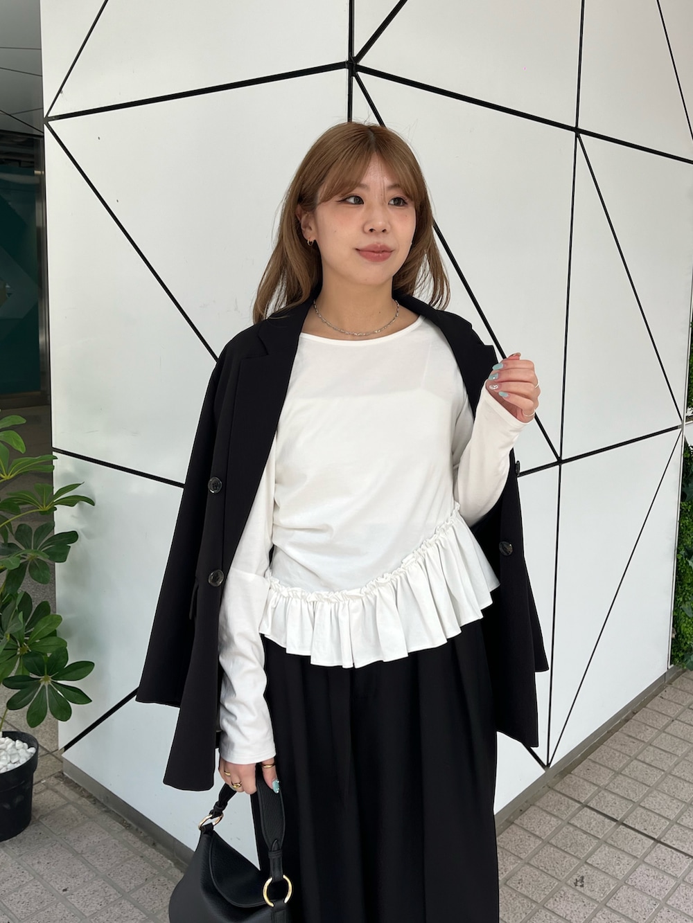 ブラック系のテーラードジャケット、ホワイト系のTシャツ/カットソー、ブラック系のその他パンツを着用したレディースの春コーディネートの3枚目の写真