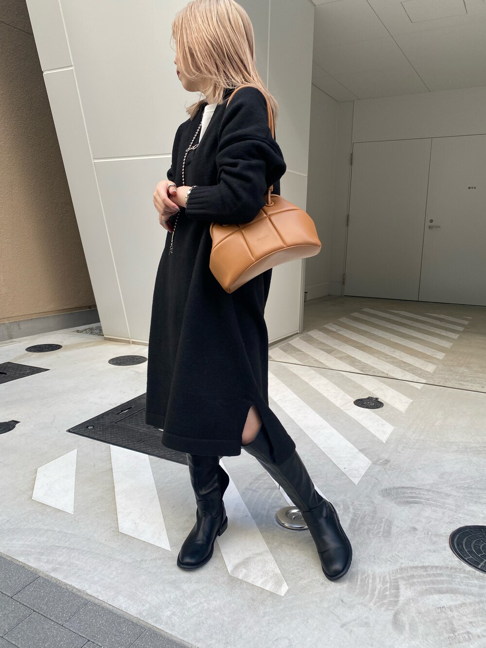 ブラック系のワンピース、ホワイト系のTシャツ/カットソー、ブラック系のブーツを着用したレディースの冬コーディネートの2枚目の写真