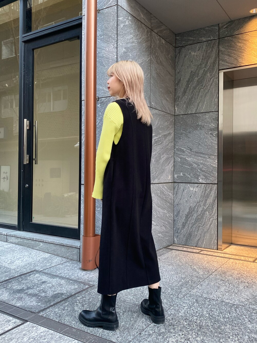 ブラック系のワンピース、ブラック系のブーツ、ブラック系のショルダーバッグを着用したレディースの冬コーディネートの4枚目の写真