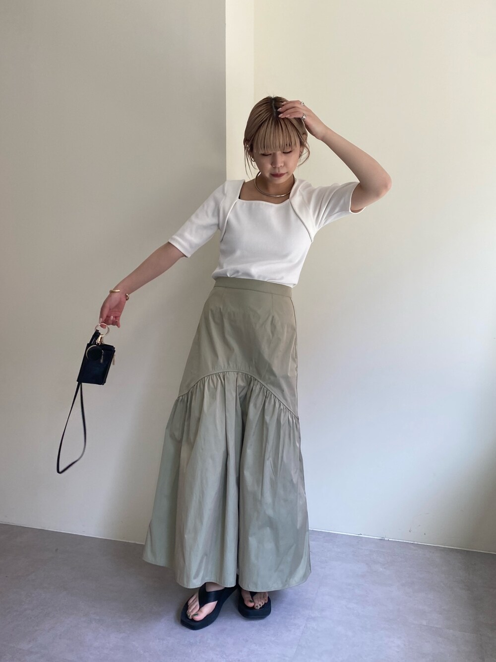 ブラック系のTシャツ/カットソー、グリーン系のスカート、シルバー系のパンプスを着用したレディースの春コーディネートの3枚目の写真