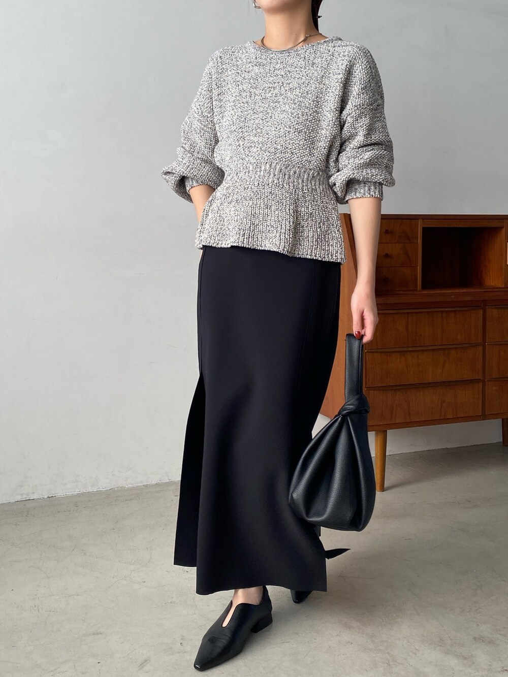 グレー系のニット/セーター、ブラック系のスカート、ブラック系のハンドバッグを着用したレディースの冬コーディネートの3枚目の写真