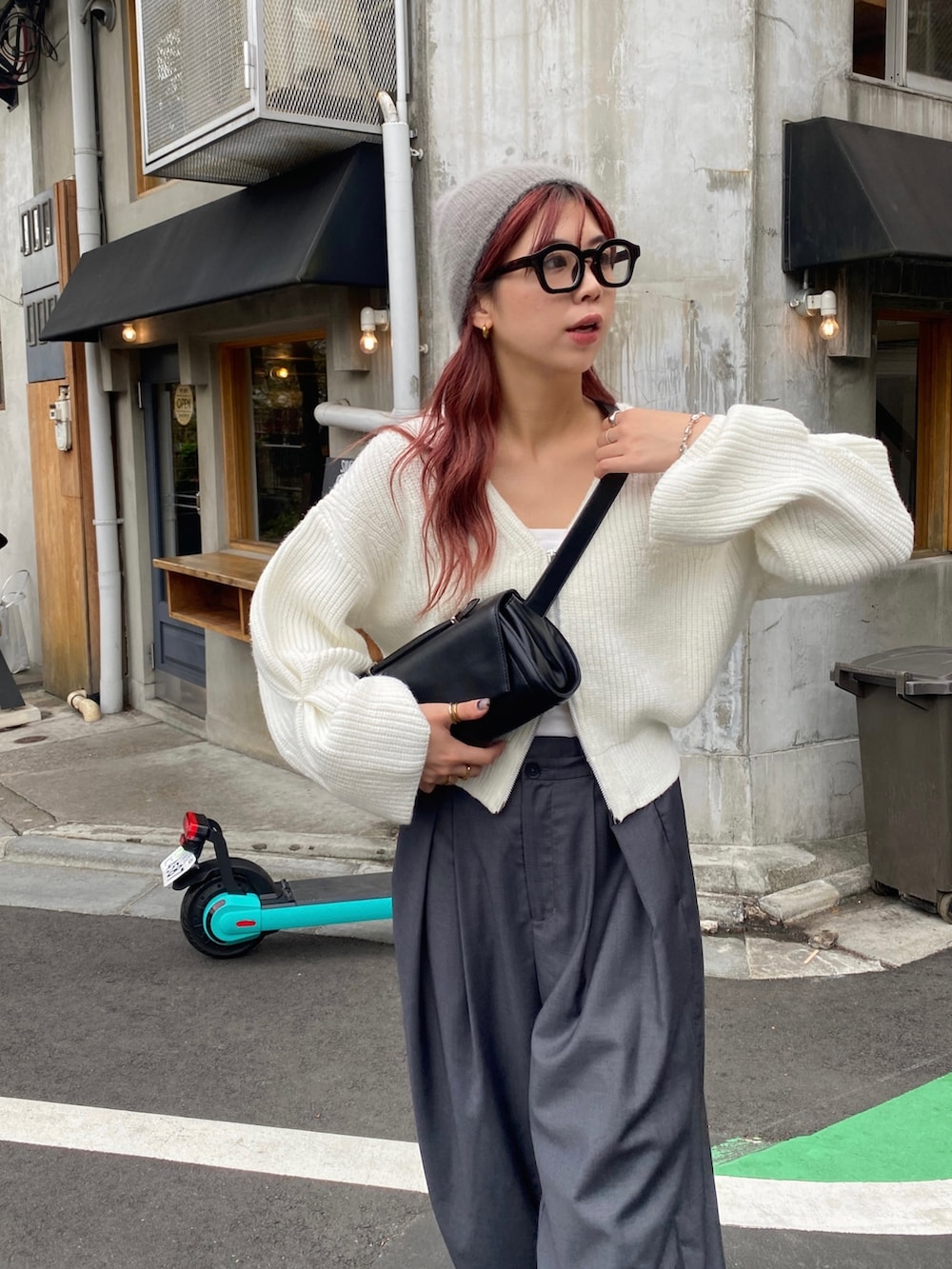 グレー系のパンツ、ブルー系のスニーカー、ブラック系のショルダーバッグを着用したレディースの秋コーディネートの3枚目の写真