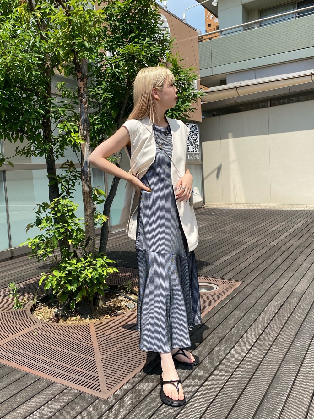 ブラック系のワンピース、ホワイト系のベスト、ホワイト系のショルダーバッグを着用したレディースの夏コーディネートの2枚目の写真