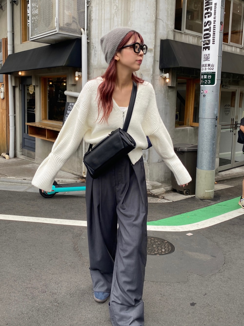 グレー系のパンツ、ブルー系のスニーカー、ブラック系のショルダーバッグを着用したレディースの秋コーディネートの2枚目の写真