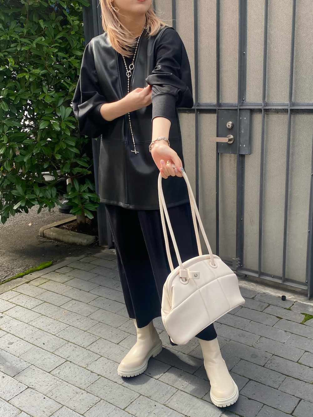 ブラック系のワンピース、ブラック系のベスト、ホワイト系のブーツを着用したレディースの秋コーディネートの4枚目の写真