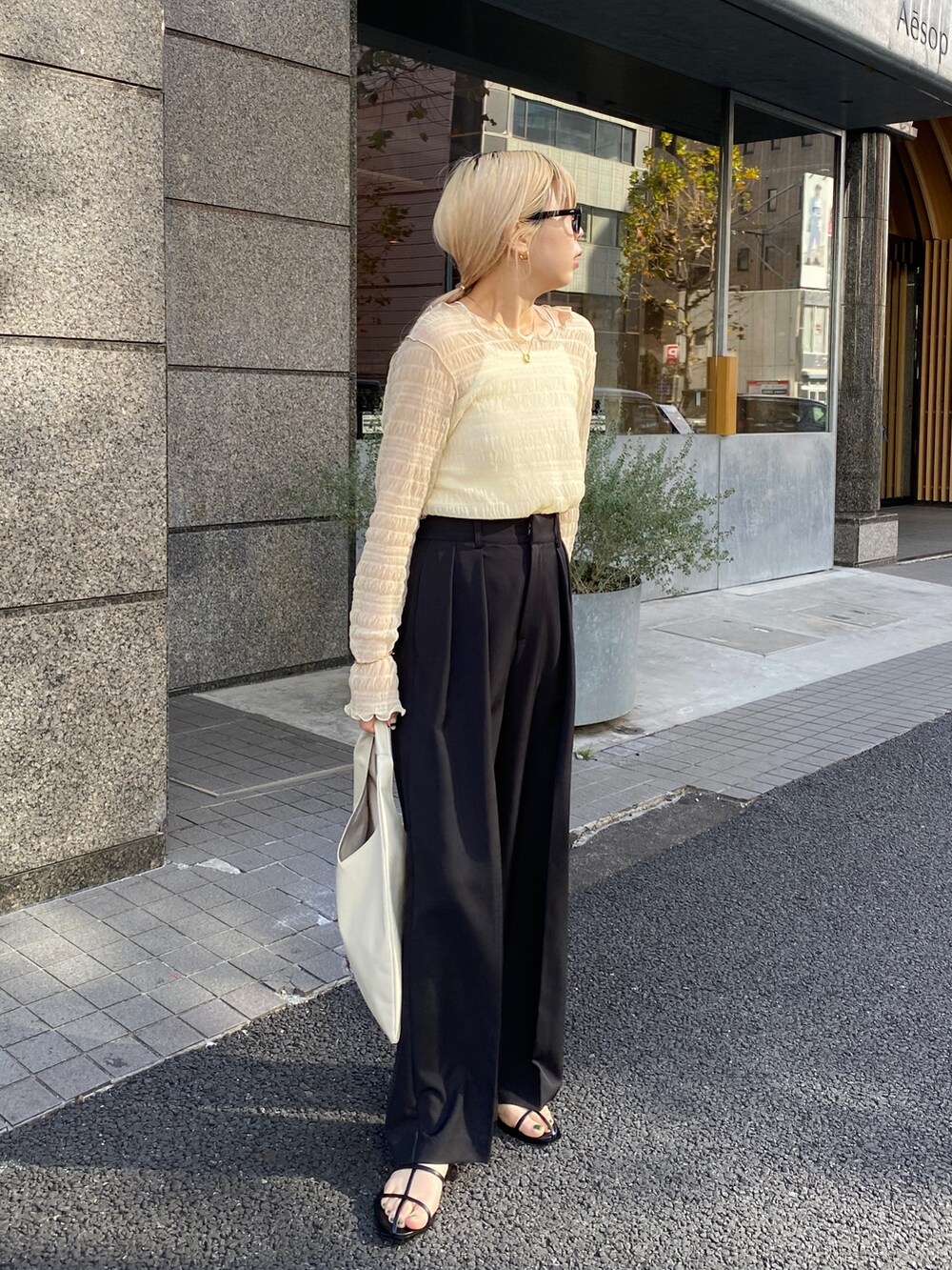 ベージュ系のTシャツ/カットソー、ブラック系のその他パンツ、ホワイト系のサンダルを着用したレディースの冬コーディネートの2枚目の写真