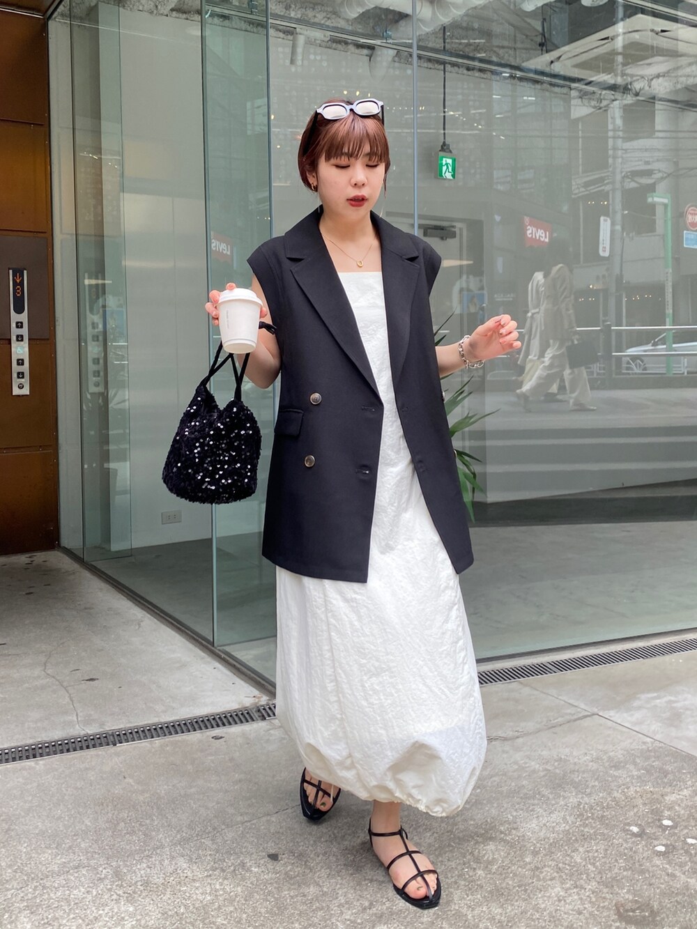 ブラック系のベスト、ホワイト系のワンピース、ブラック系のその他シューズを着用したレディースの春コーディネートの3枚目の写真