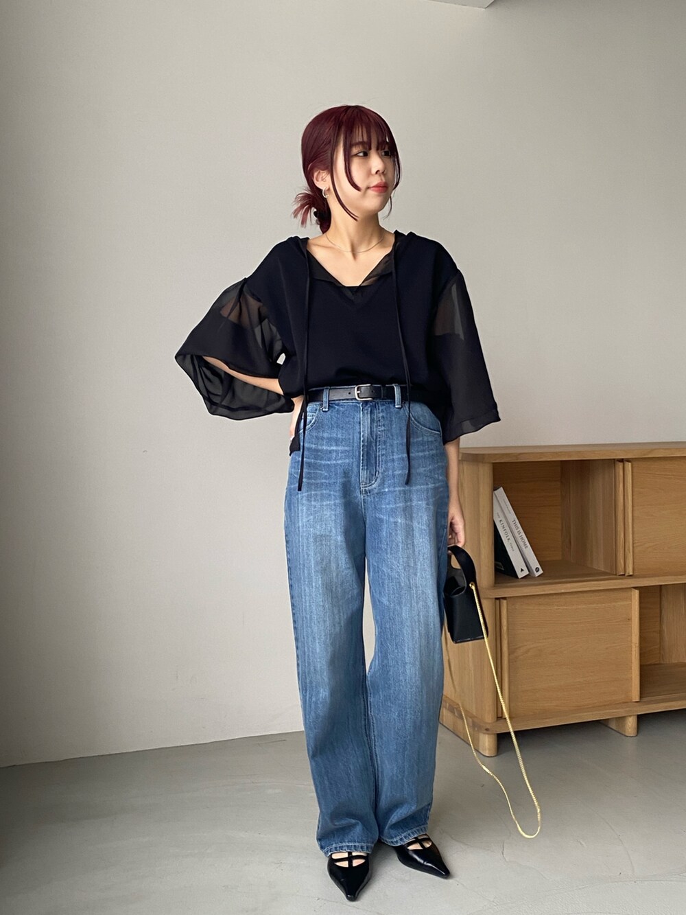 ブラック系のトップス、ブルー系のデニムパンツ、ホワイト系のパンプスを着用したレディースの冬コーディネートの2枚目の写真