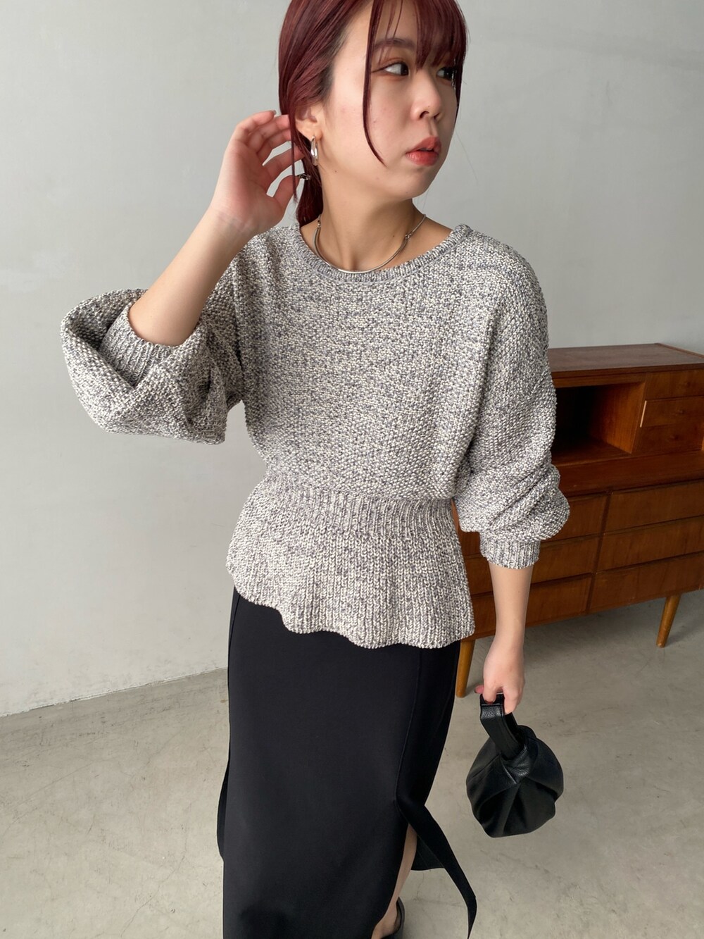 グレー系のニット/セーター、ブラック系のスカート、ブラック系のハンドバッグを着用したレディースの冬コーディネートの4枚目の写真