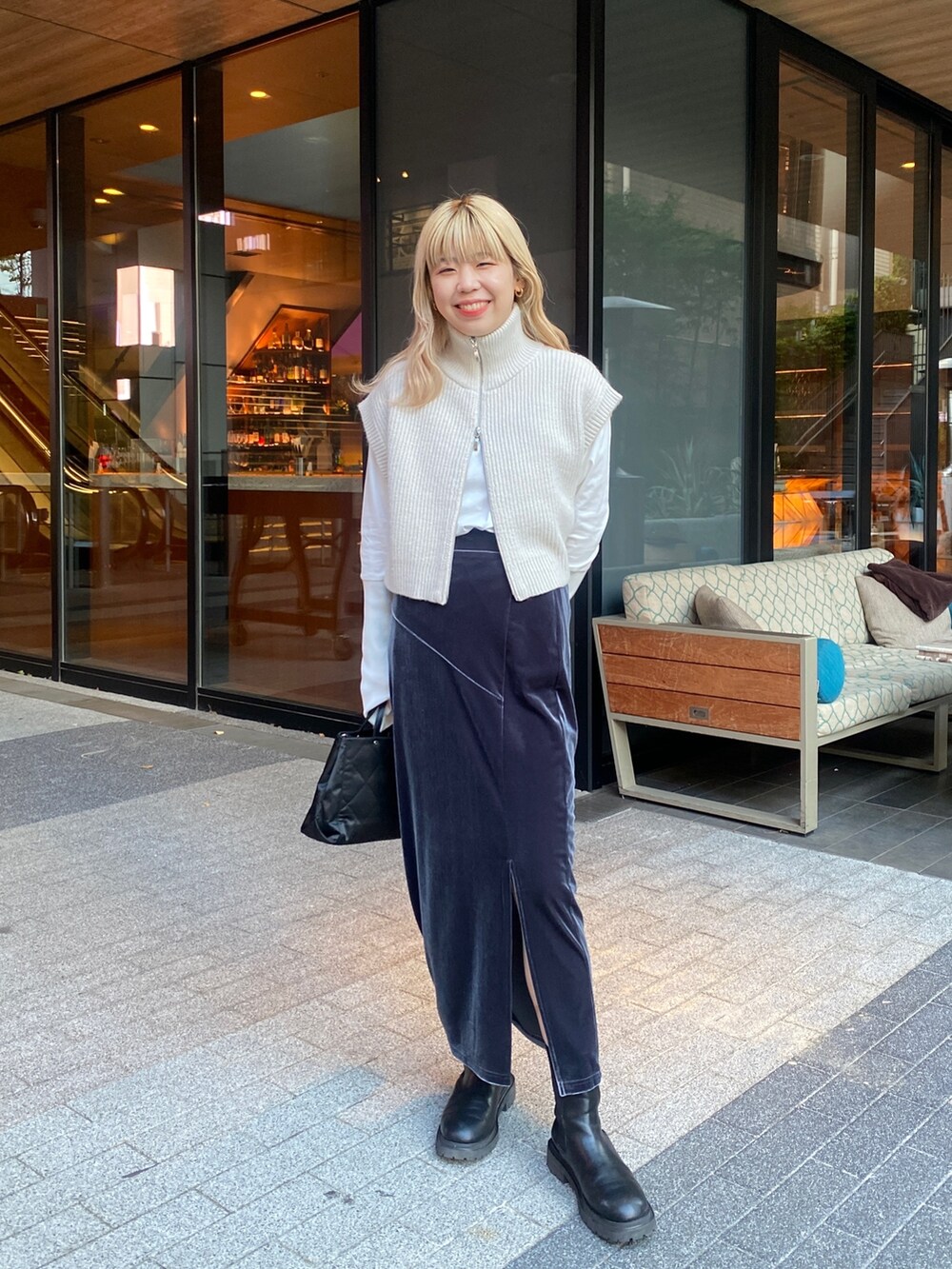 グレー系のスカート、ホワイト系のベスト、ホワイト系のTシャツ/カットソーを着用したレディースの秋コーディネートの2枚目の写真