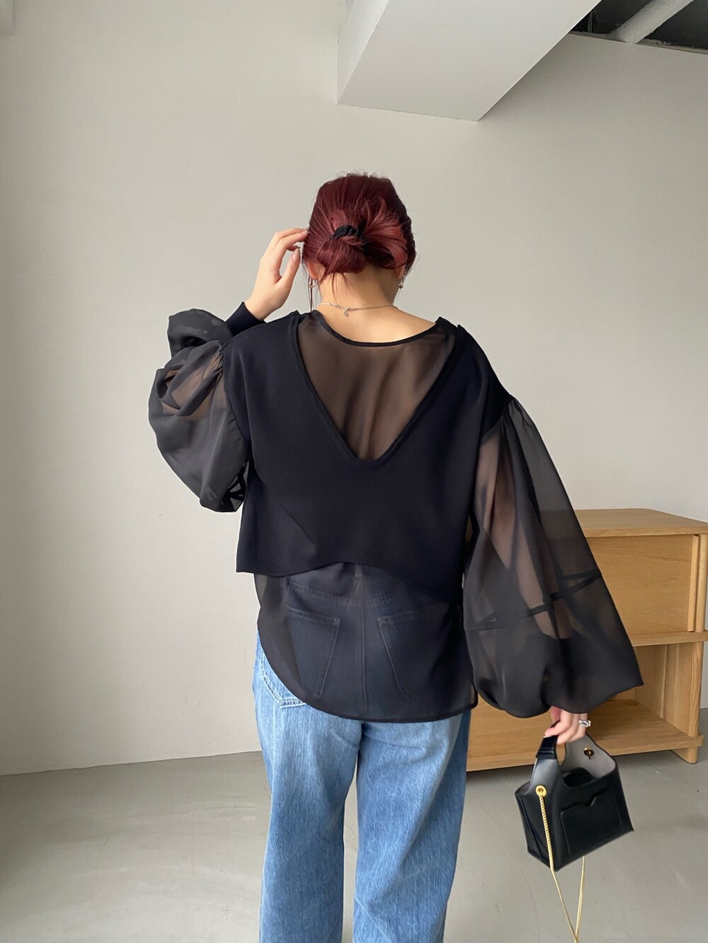 ブラック系のトップス、ブルー系のデニムパンツ、ホワイト系のパンプスを着用したレディースの冬コーディネートの3枚目の写真