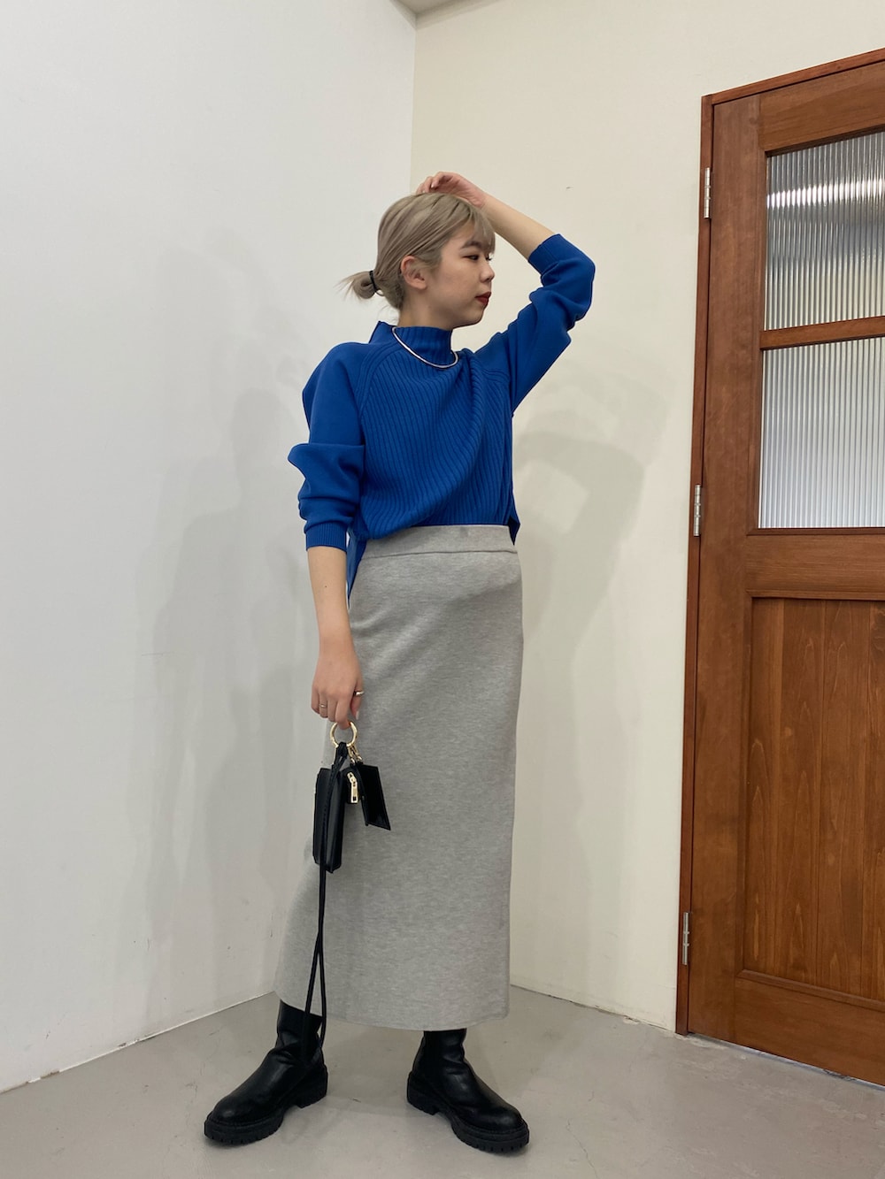 ブルー系のニット/セーター、ブラック系のブーツ、ブラック系のショルダーバッグを着用したレディースの冬コーディネートの2枚目の写真