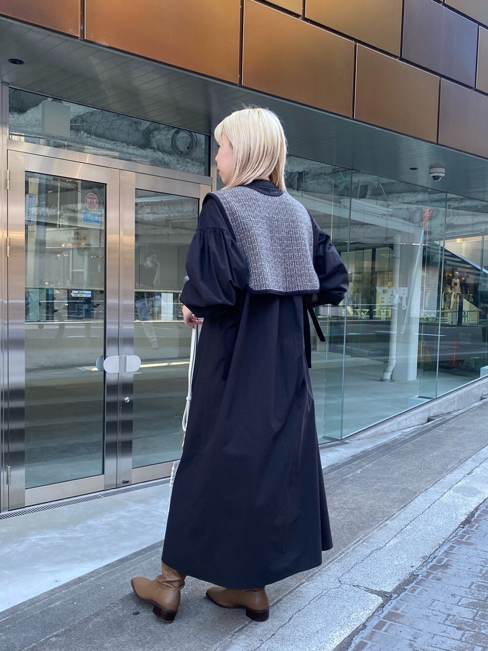 ブラック系のニット/セーター、ブラック系のワンピース、ブラウン系のブーツを着用したレディースの夏コーディネートの3枚目の写真