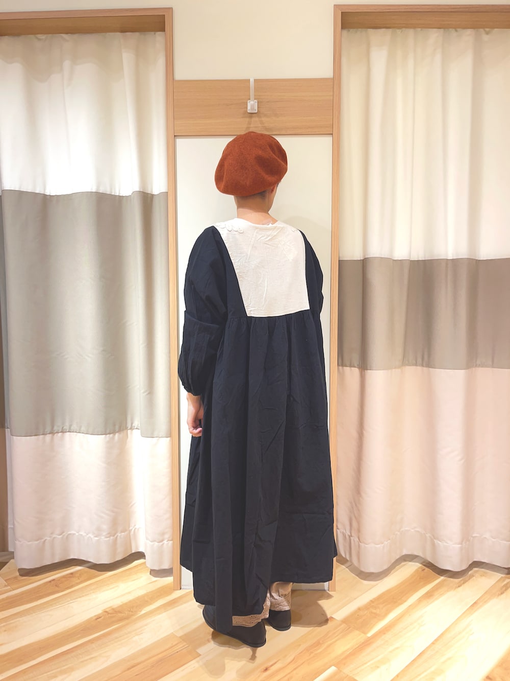 ブラック系のワンピース、ブラック系のローファー、オレンジ系のハンチング/ベレー帽を着用したレディースの秋コーディネートの2枚目の写真