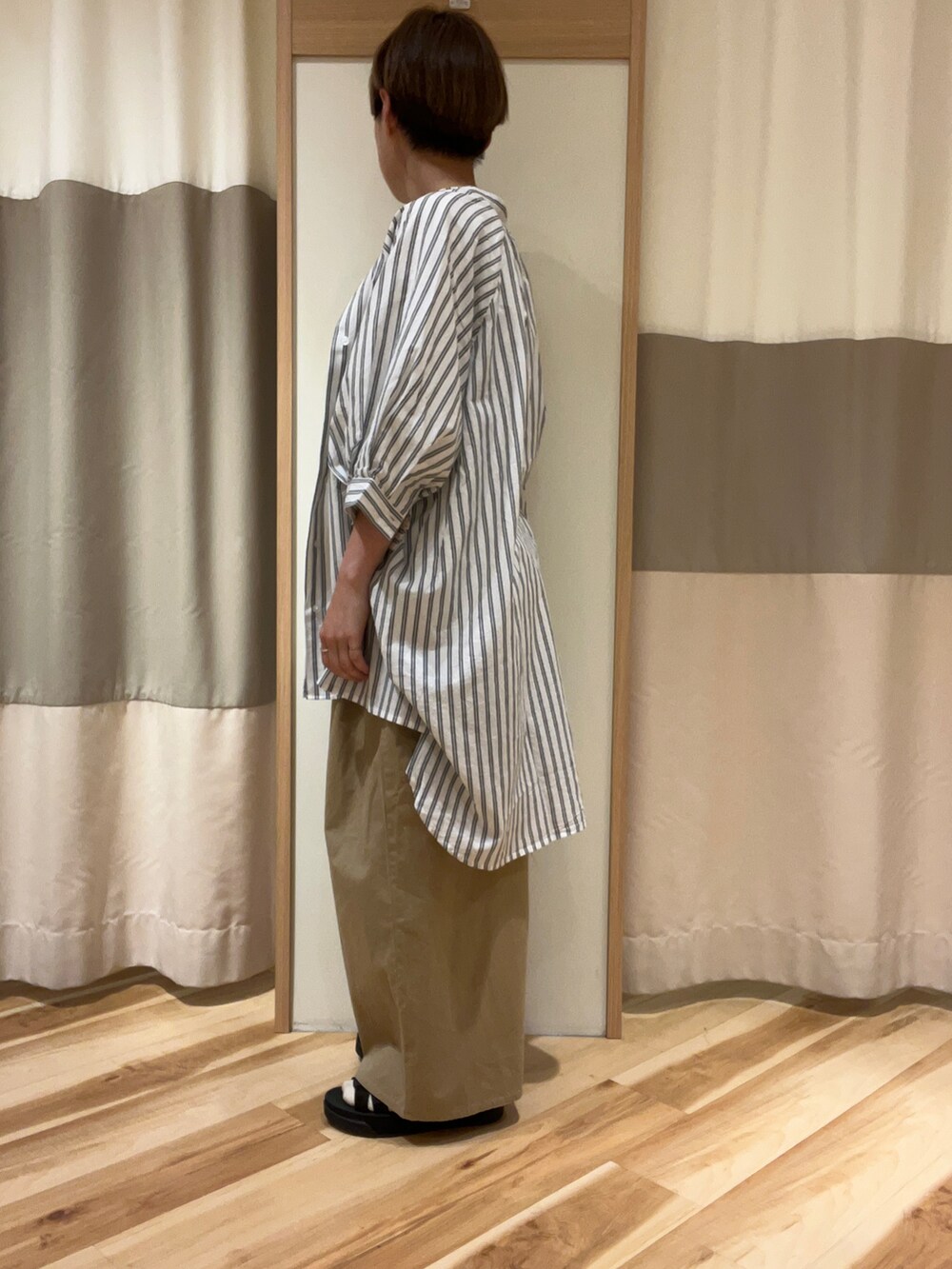 ブラック系のサンダル、ベージュ系のその他パンツ、ホワイト系のTシャツ/カットソーを着用したレディースの春コーディネートの2枚目の写真