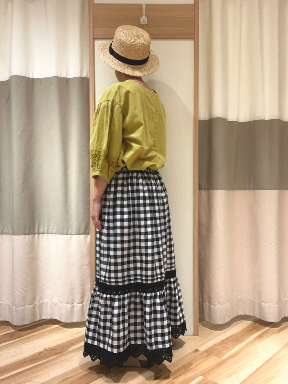 イエロー系のシャツ/ブラウス、ブラック系のスカート、ベージュ系のサンダルを着用したレディースの春コーディネートの2枚目の写真