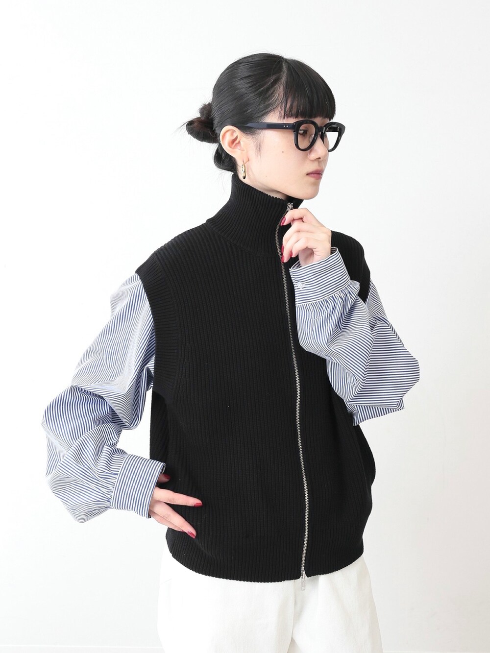 ブラック系のベスト、ホワイト系のデニムパンツ、ホワイト系のスニーカーを着用したレディースの冬コーディネートの2枚目の写真