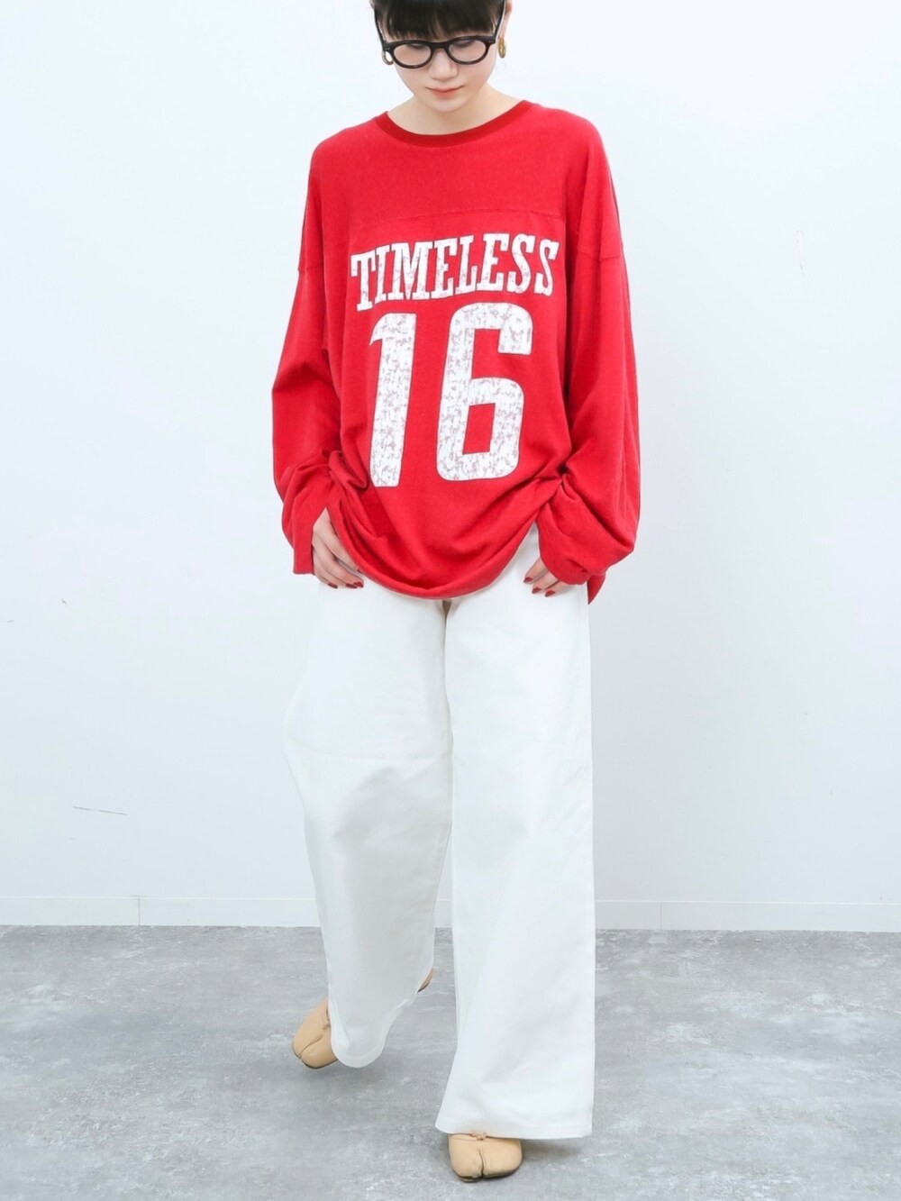 レッド系のTシャツ/カットソー、ホワイト系のデニムパンツ、ベージュ系のバレエシューズを着用したレディースの冬コーディネートの2枚目の写真