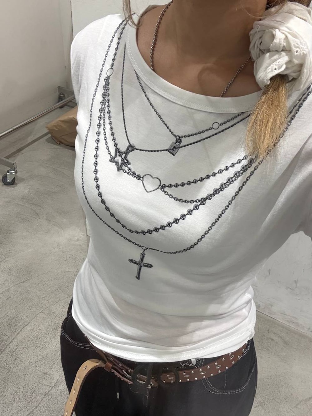 ブラック系のデニムパンツ、ホワイト系のTシャツ/カットソー、ブラウン系のベルトを着用したレディースの秋コーディネートの2枚目の写真