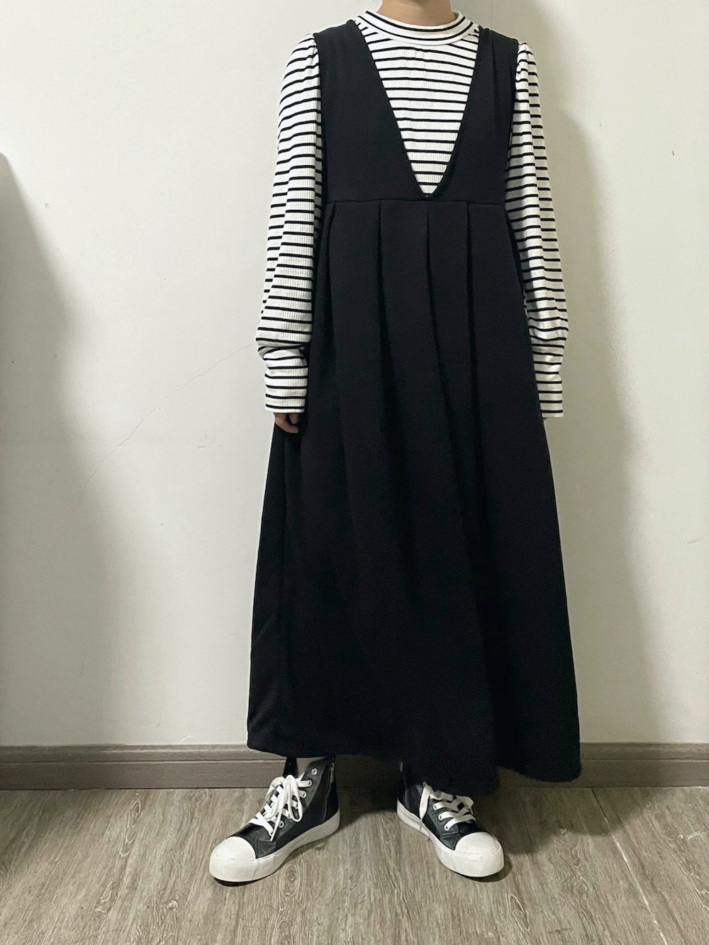 ホワイト系のTシャツ/カットソー、ブラック系のジャンパースカート、ベージュ系のショルダーバッグを着用したレディースの冬コーディネートの2枚目の写真