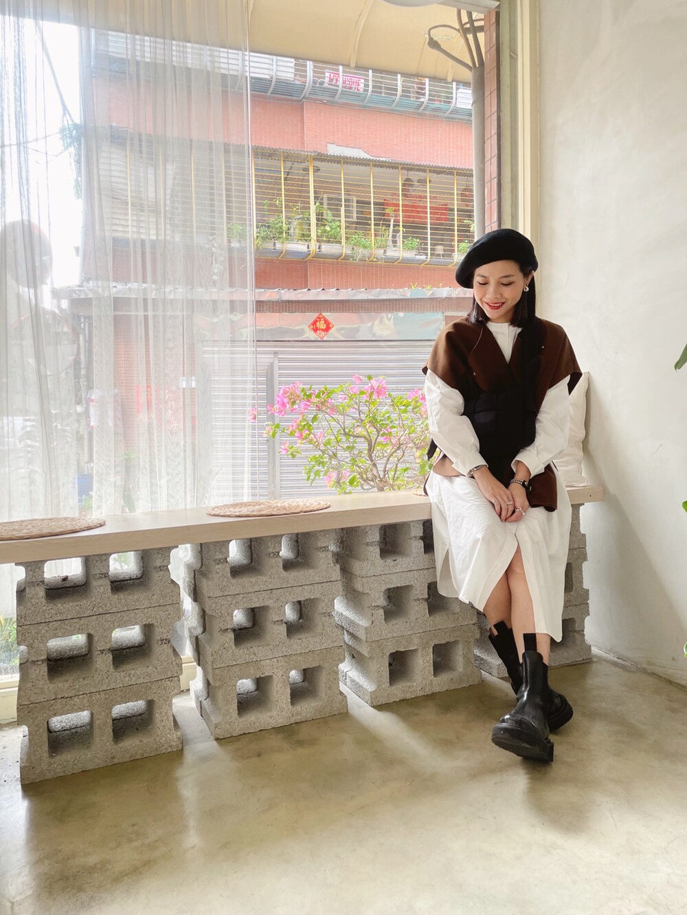 ブラウン系のベスト、ホワイト系のシャツワンピース、ブラック系のブーツを着用したレディースの春コーディネートの2枚目の写真