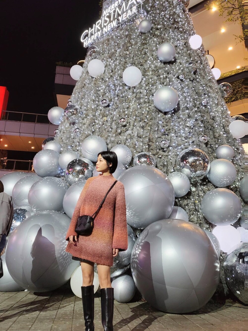 ブラック系のブーツ、レッド系のニット/セーター、ブラック系のスカートを着用したレディースの冬コーディネートの2枚目の写真