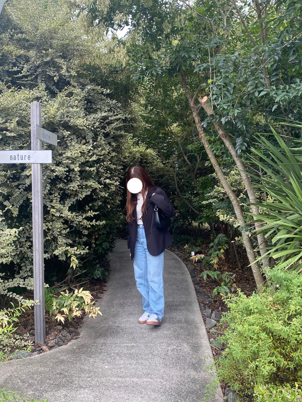 ブラック系のテーラードジャケット、ブルー系のデニムパンツ、ホワイト系のスニーカーを着用したレディースの秋コーディネートの3枚目の写真