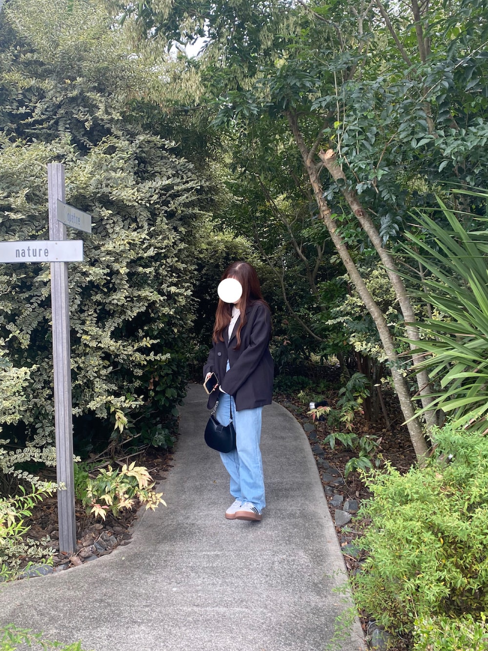 ブラック系のテーラードジャケット、ブルー系のデニムパンツ、ホワイト系のスニーカーを着用したレディースの秋コーディネートの2枚目の写真