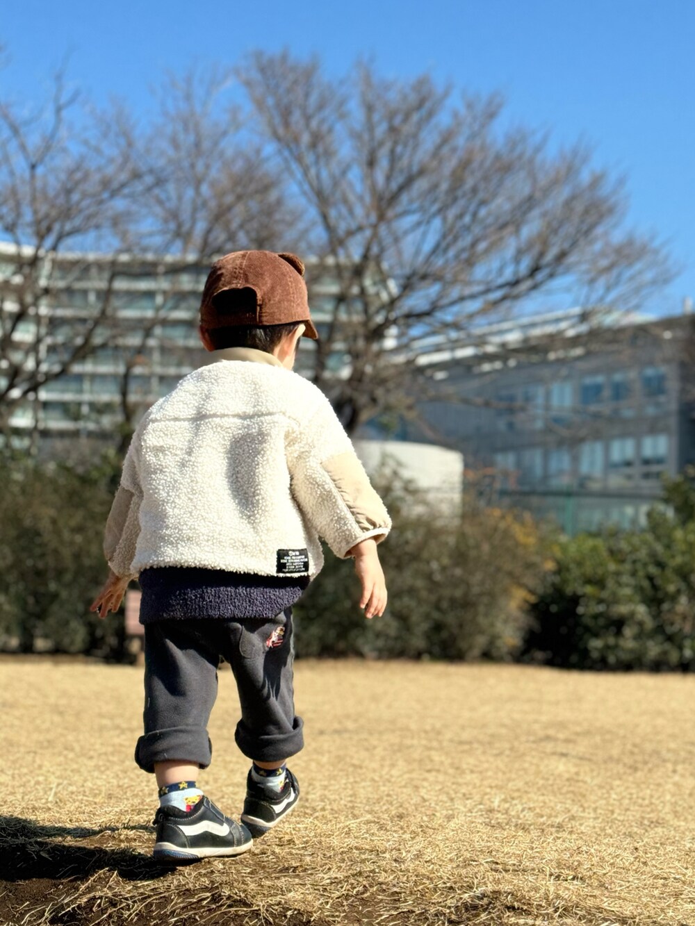 ホワイト系のジャケット/アウター、ブラック系のスニーカー、グレー系のパンツを着用したキッズの春コーディネートの2枚目の写真