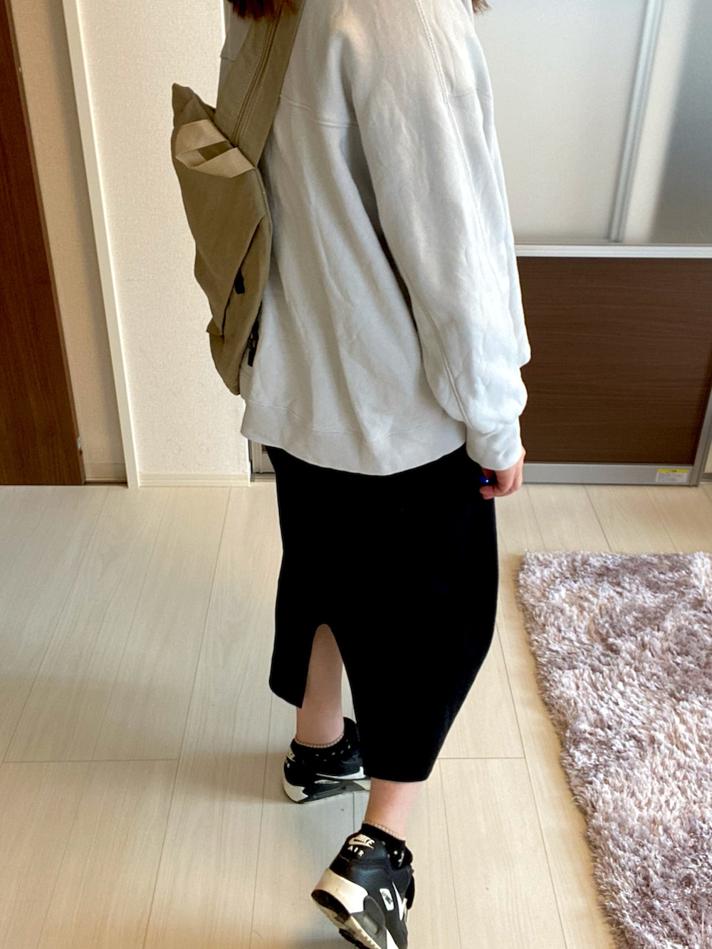 グレー系のスウェット、ベージュ系のバックパック/リュック、ブラック系のスカートを着用したレディースの冬コーディネートの2枚目の写真