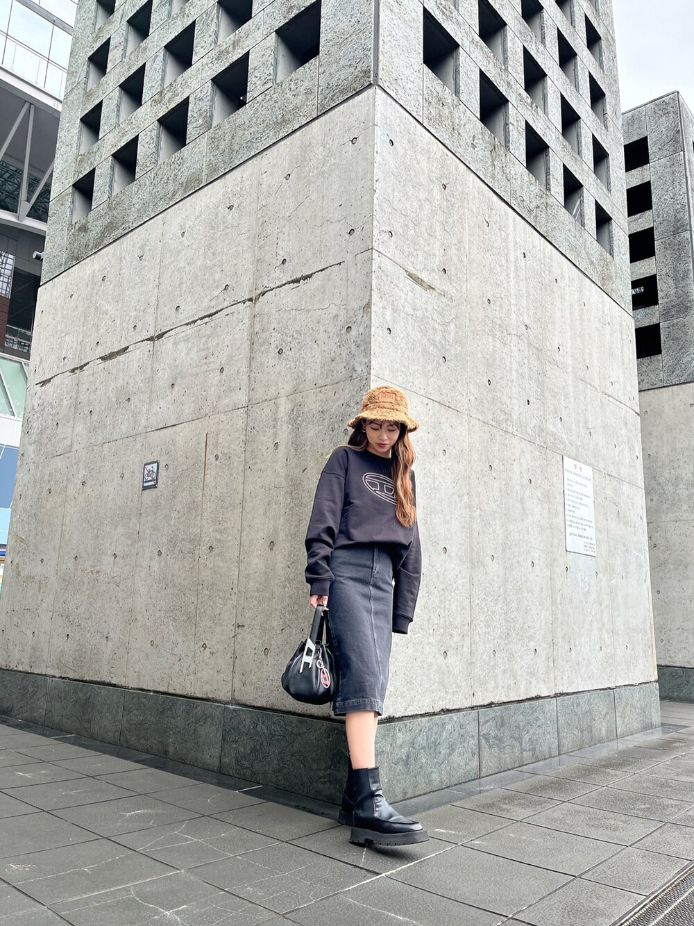 ブラック系のハンドバッグ、ブラック系のスウェット、ブラック系のスカートを着用したレディースの冬コーディネートの2枚目の写真