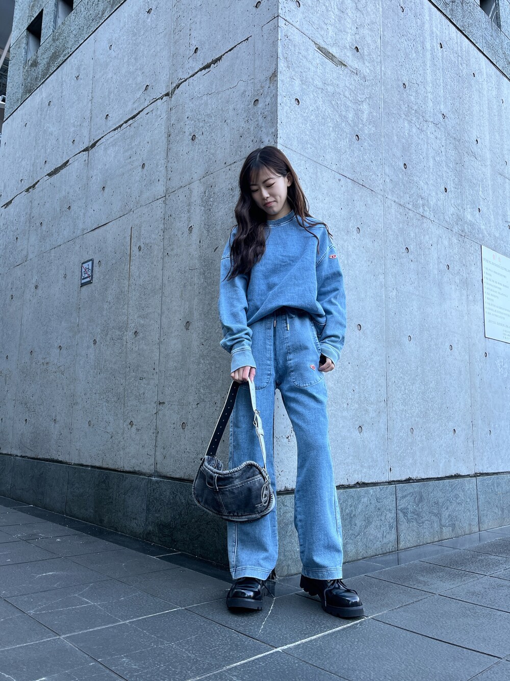 ブルー系のスウェット、ブルー系のデニムパンツ、ブラック系のハンドバッグを着用したレディースの冬コーディネートの2枚目の写真