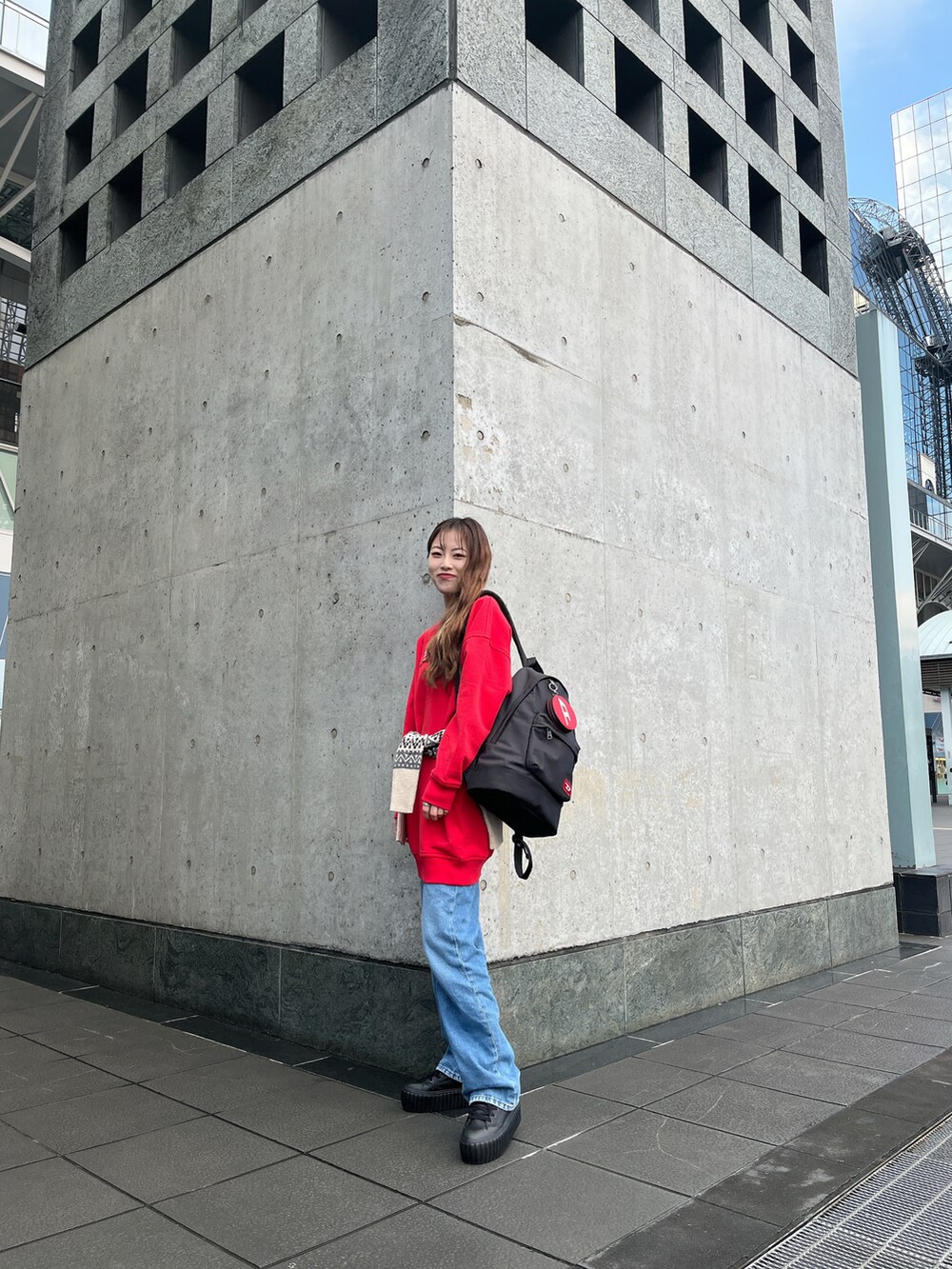 レッド系のワンピース、ブラック系のバックパック/リュック、ブルー系のデニムパンツを着用したレディースの冬コーディネートの2枚目の写真