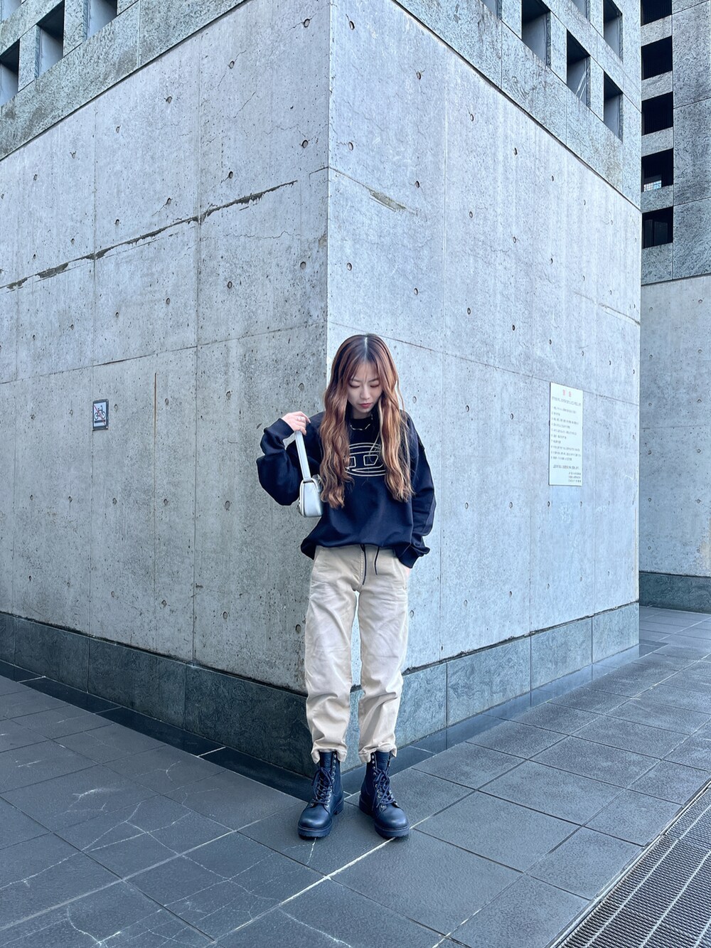 ブラック系のスウェット、ベージュ系のパンツ、ホワイト系のショルダーバッグを着用したレディースの冬コーディネートの2枚目の写真