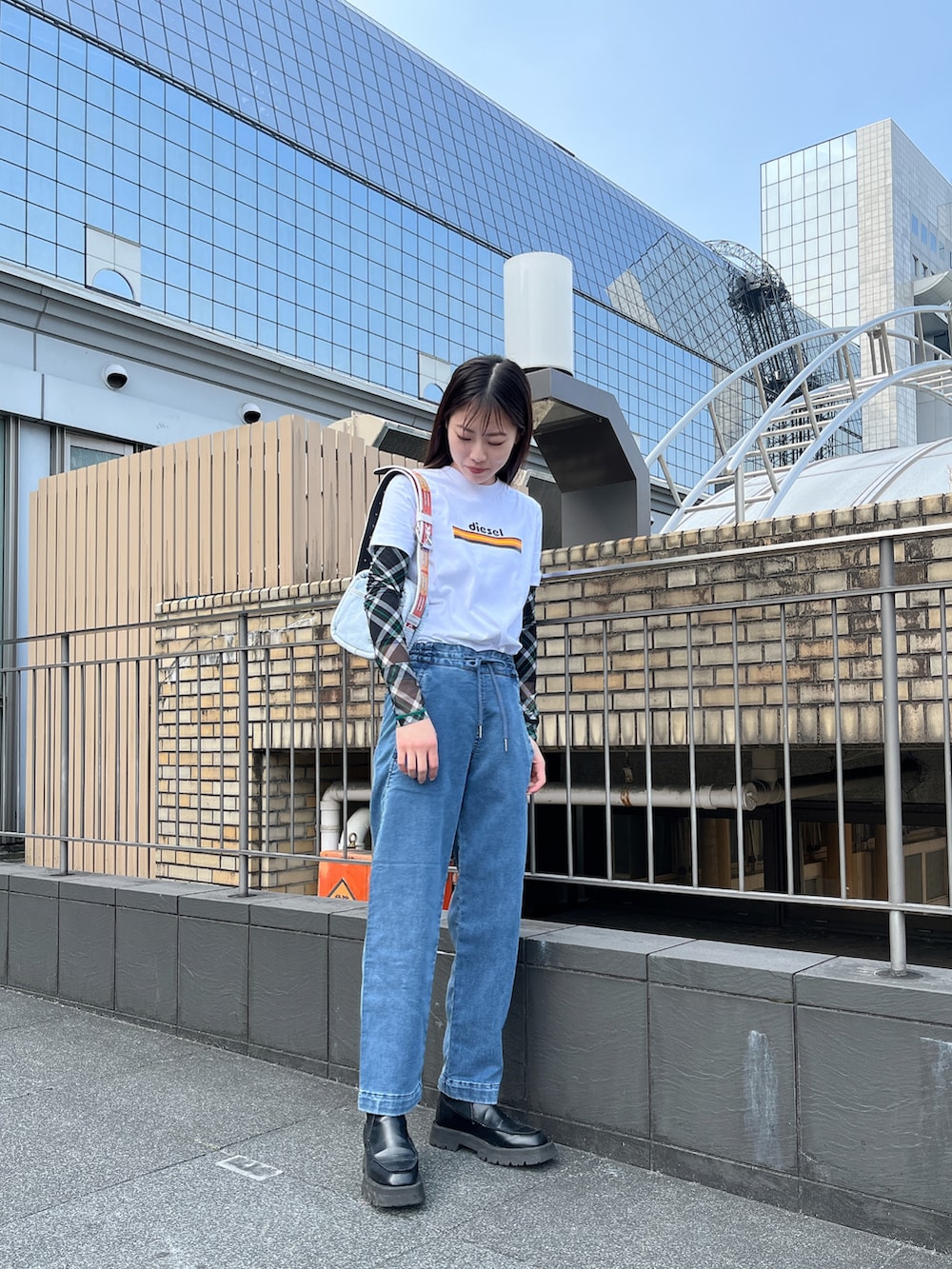 ブルー系のデニムパンツ、ブルー系のハンドバッグ、ホワイト系のTシャツ/カットソーを着用したレディースの春コーディネートの2枚目の写真