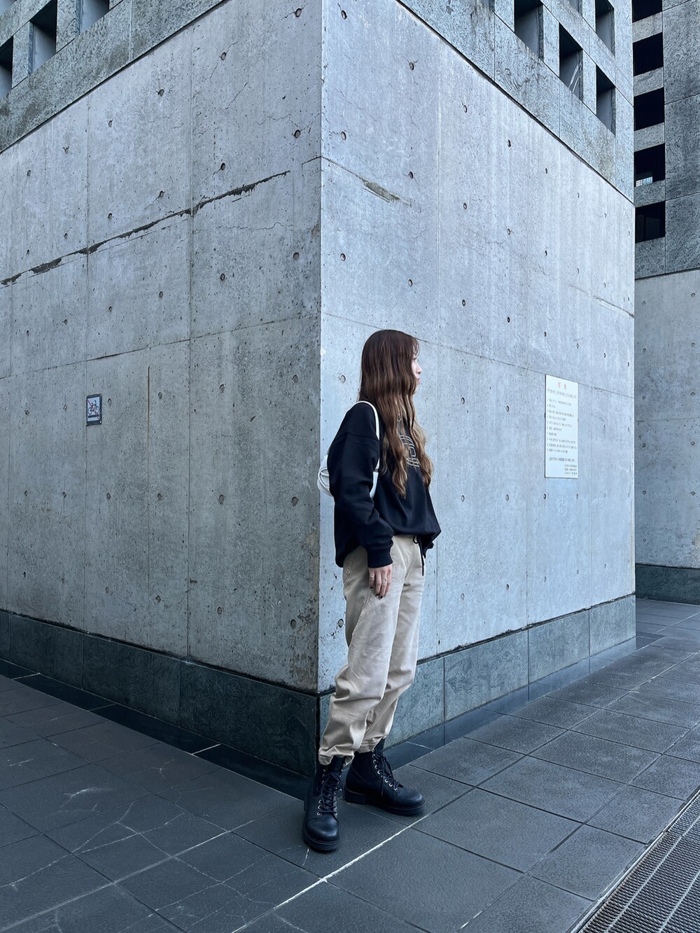 ブラック系のスウェット、ベージュ系のパンツ、ホワイト系のショルダーバッグを着用したレディースの冬コーディネートの3枚目の写真