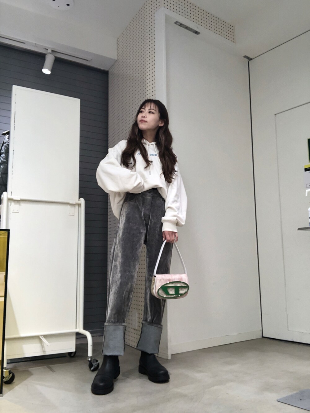 グレー系のデニムパンツ、グリーン系のショルダーバッグ、ブラック系のブーツを着用したレディースの秋コーディネートの2枚目の写真