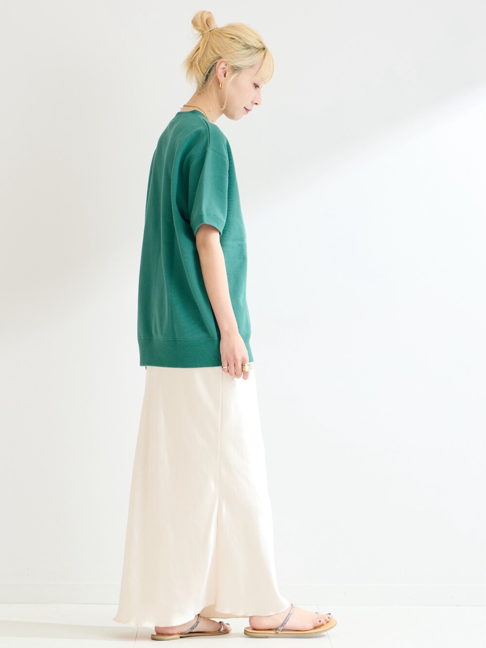 グリーン系のスウェット、ホワイト系のスカートを着用したレディースの春コーディネートの2枚目の写真