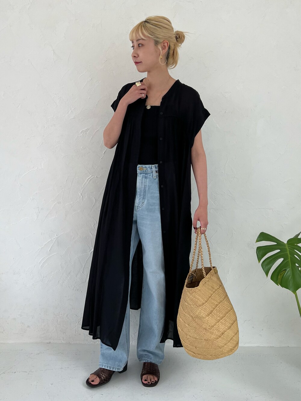 ブラック系のワンピース、ブルー系のデニムパンツを着用したレディースの春コーディネートの2枚目の写真