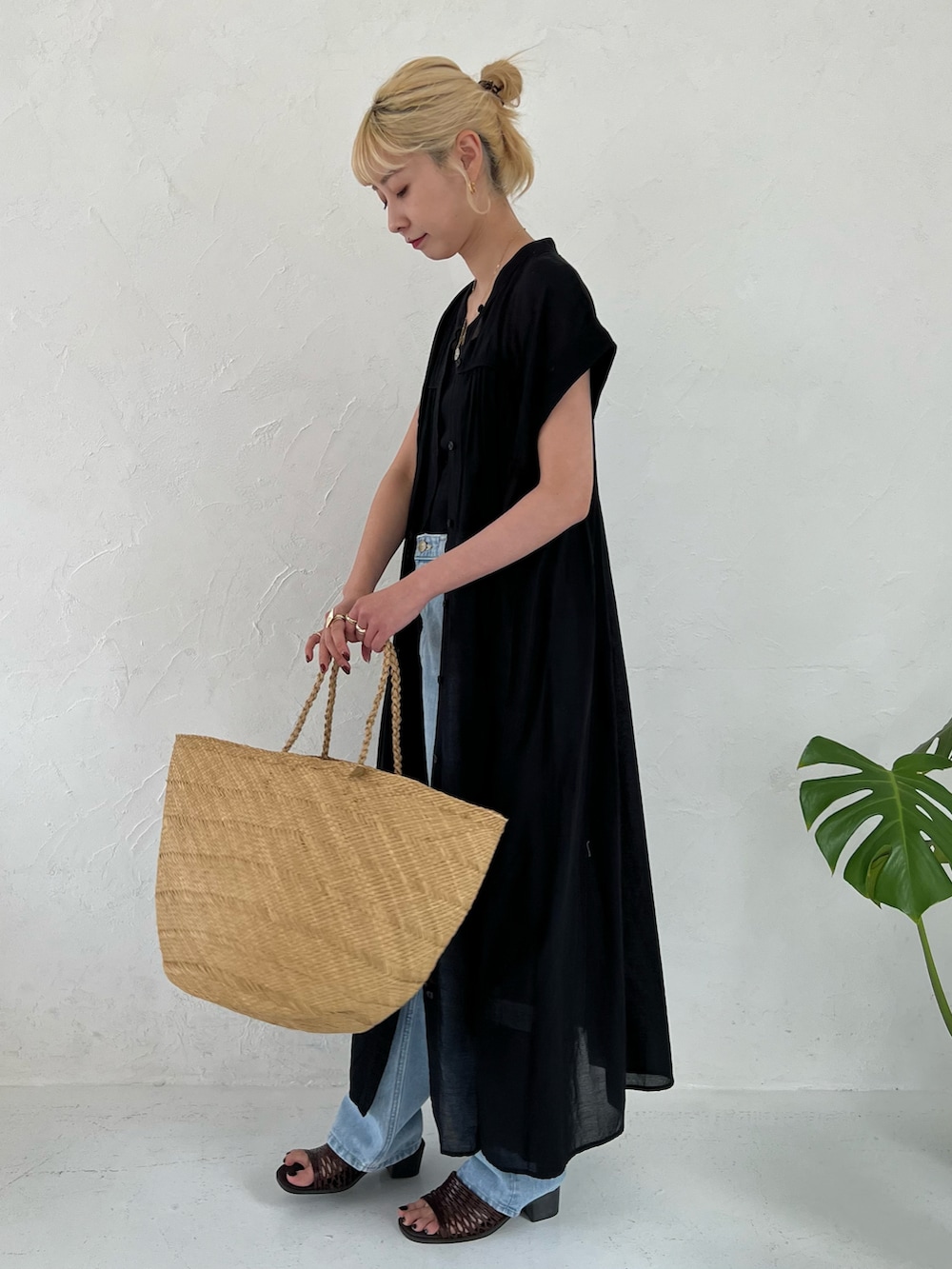 ブラック系のワンピース、ブルー系のデニムパンツを着用したレディースの春コーディネートの3枚目の写真