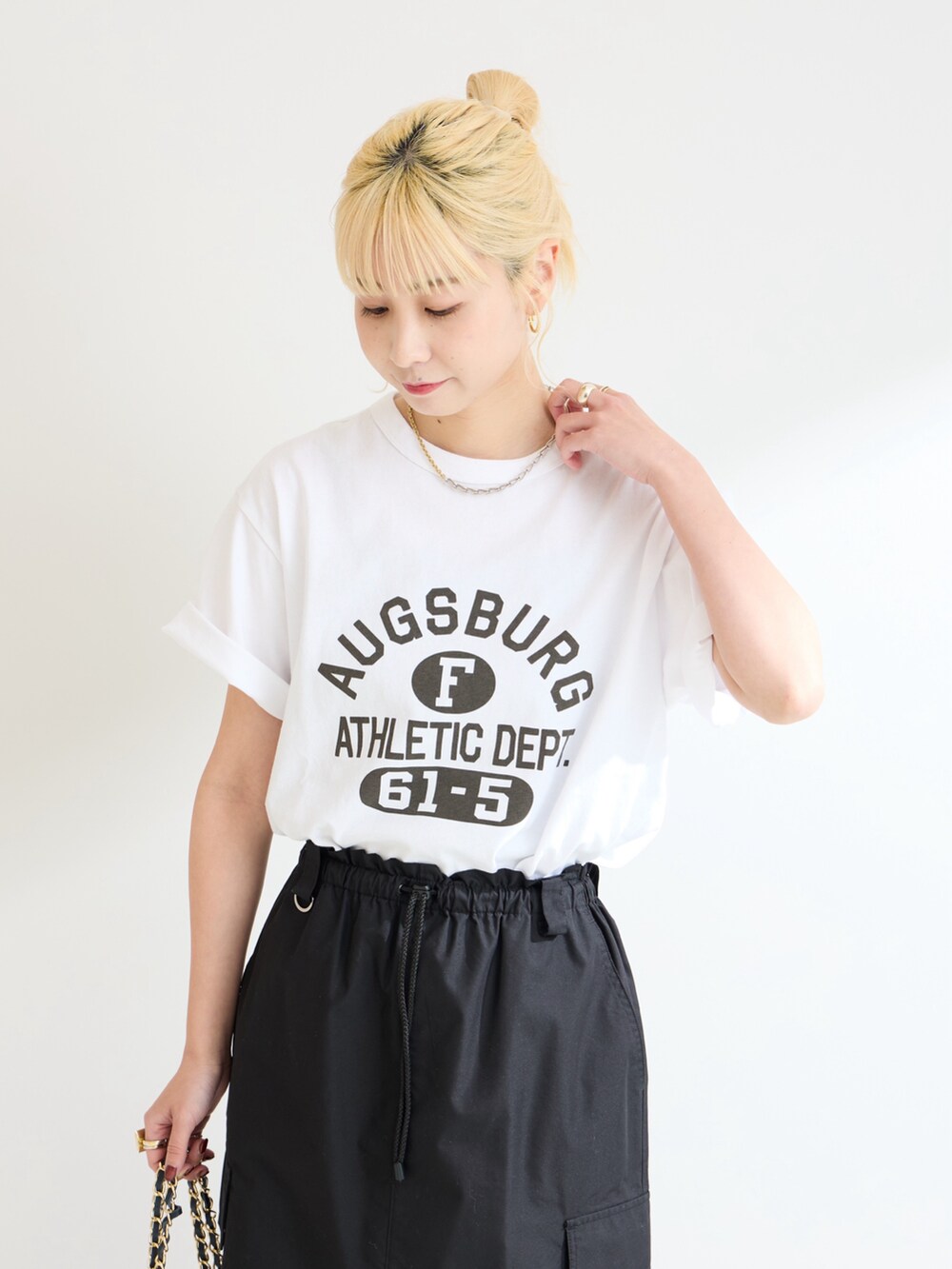 ブラック系のスカート、ホワイト系のTシャツ/カットソーを着用したレディースの春コーディネートの4枚目の写真