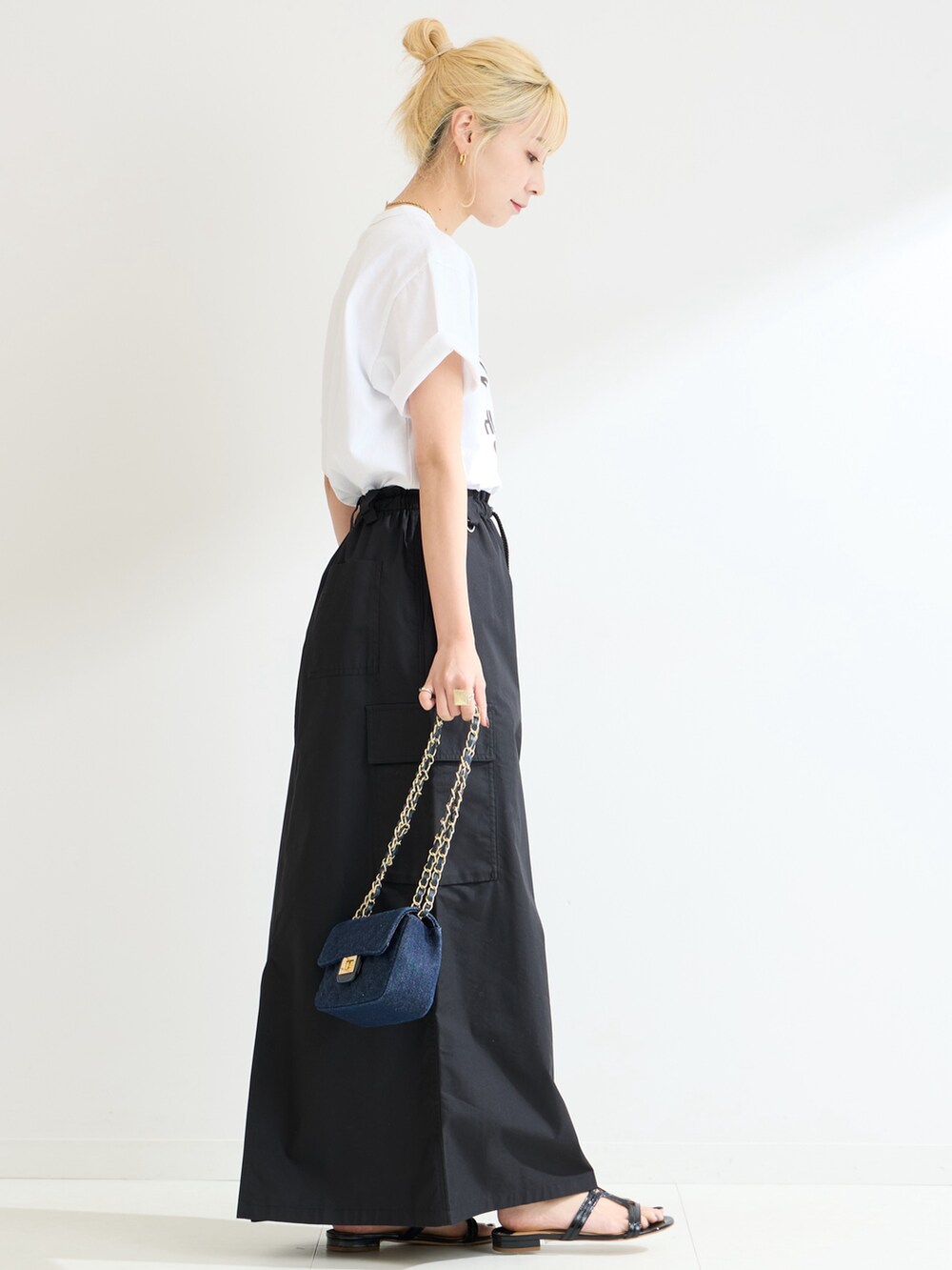 ブラック系のスカート、ホワイト系のTシャツ/カットソーを着用したレディースの春コーディネートの2枚目の写真