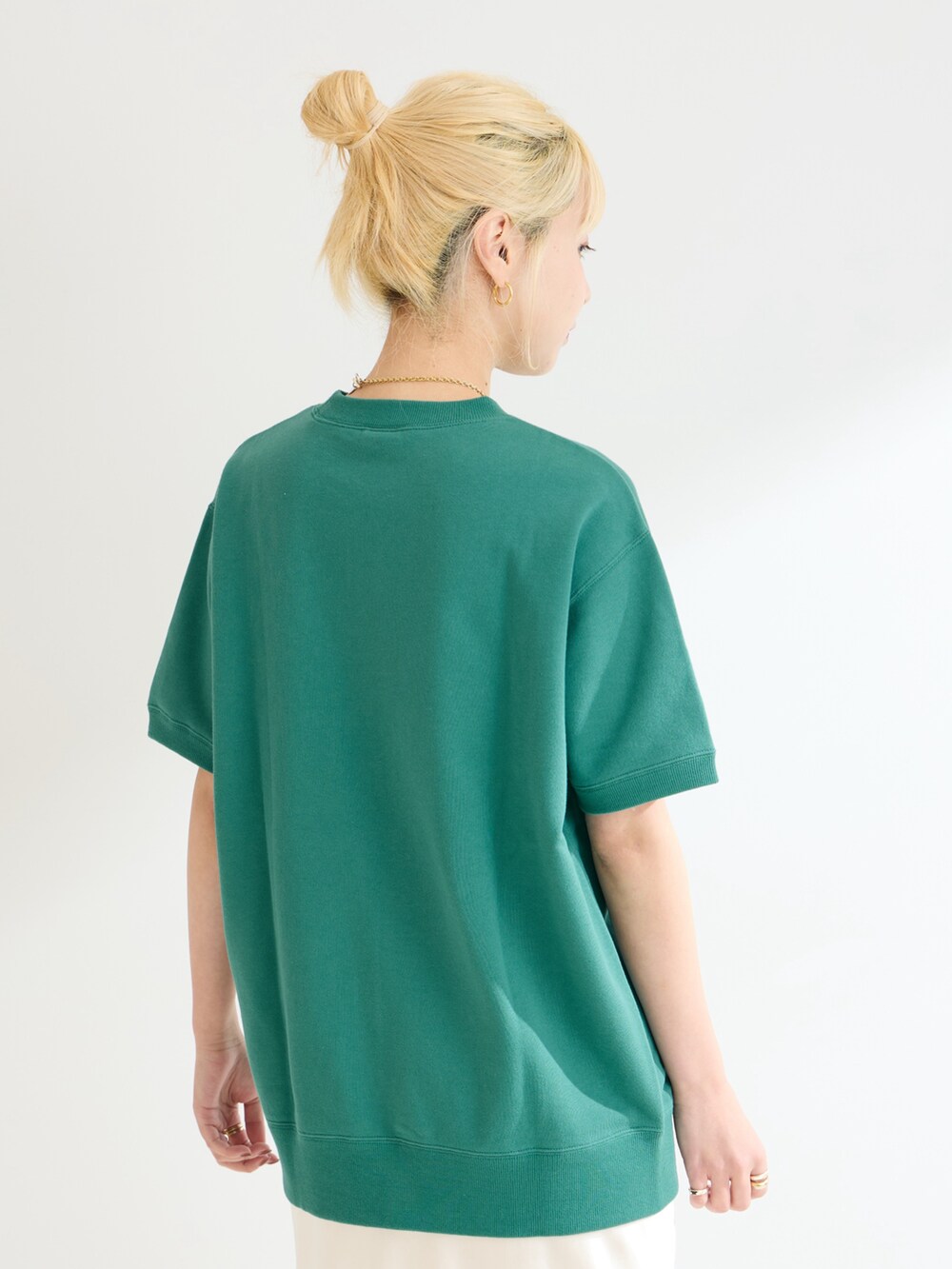 グリーン系のスウェット、ホワイト系のスカートを着用したレディースの春コーディネートの5枚目の写真