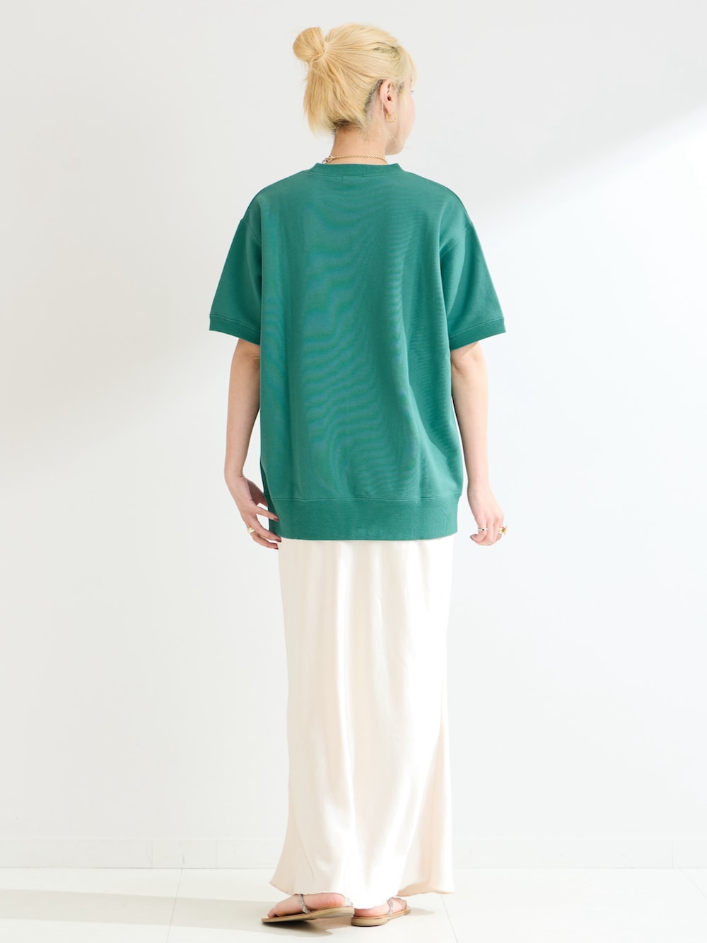 グリーン系のスウェット、ホワイト系のスカートを着用したレディースの春コーディネートの3枚目の写真