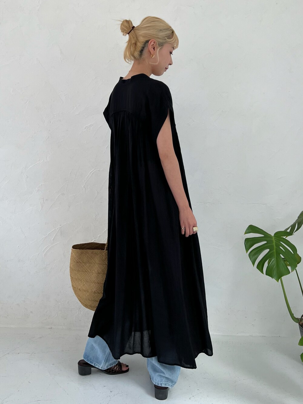 ブラック系のワンピース、ブルー系のデニムパンツを着用したレディースの春コーディネートの4枚目の写真