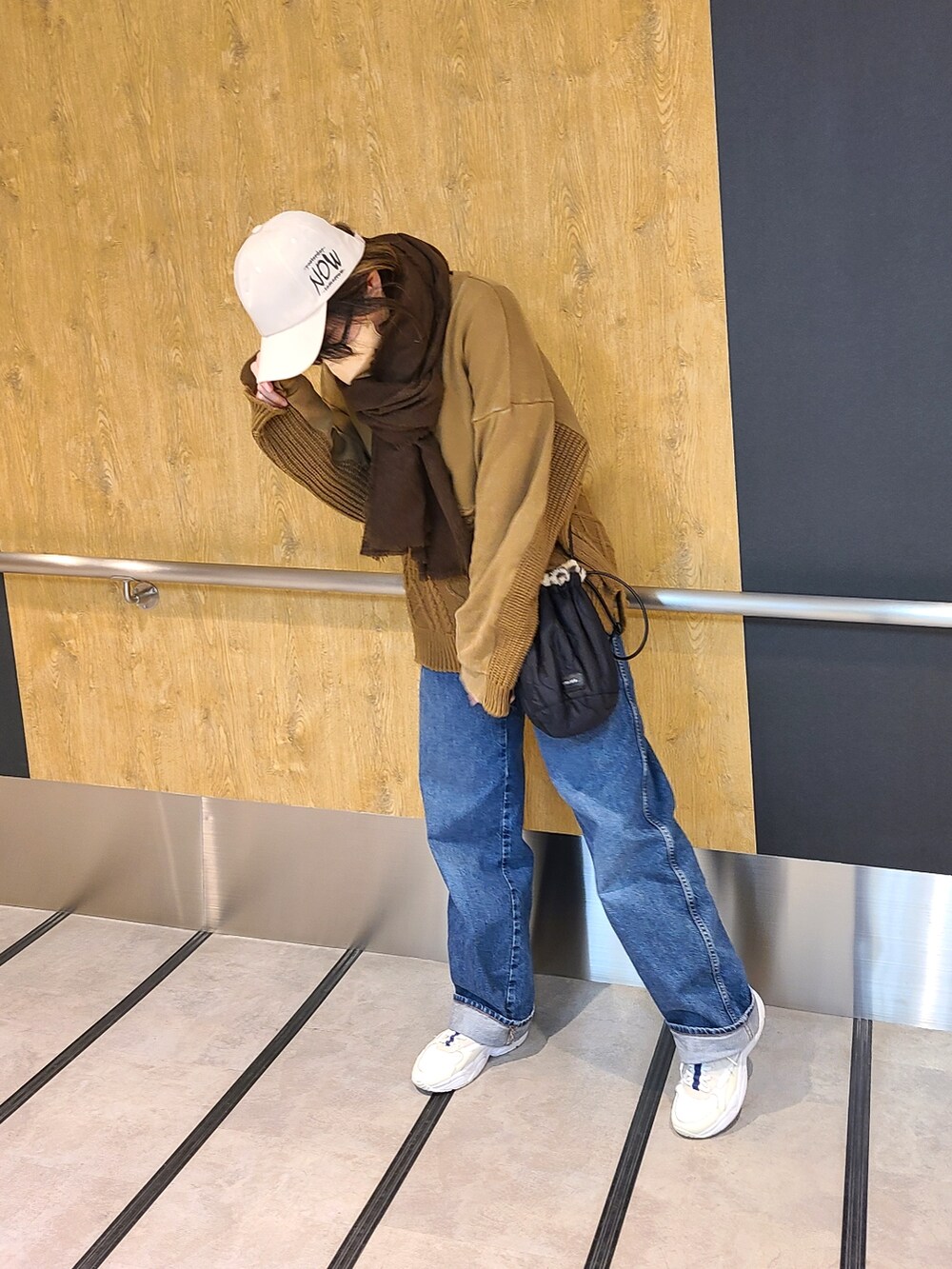 ブルー系のデニムパンツ、その他のショルダーバッグ、ブラウン系のニット/セーターを着用したレディースの冬コーディネートの2枚目の写真