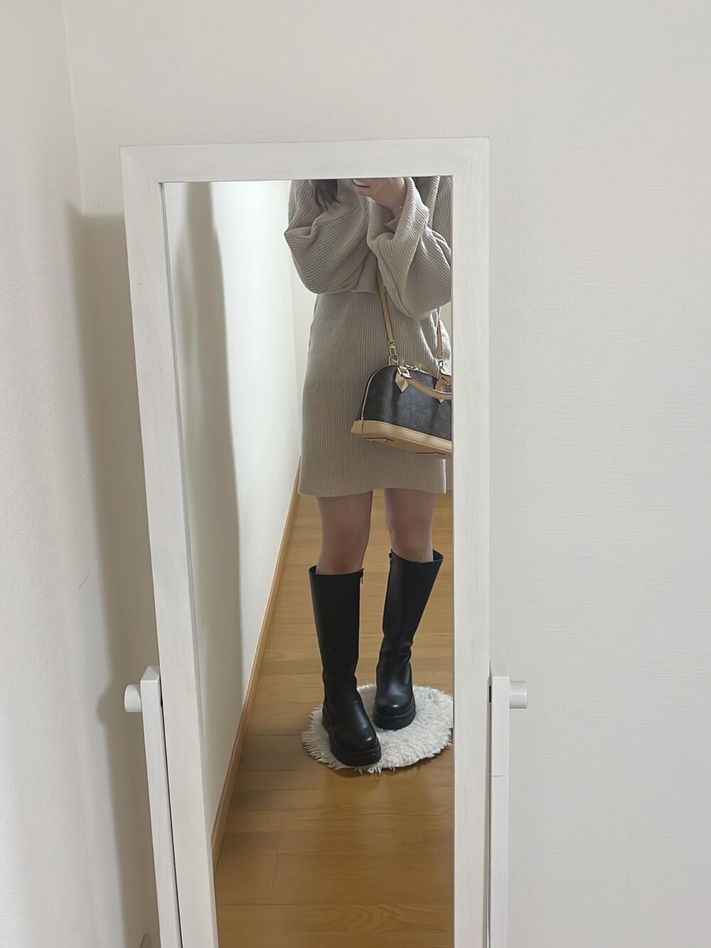 ベージュ系のワンピース、ブラック系のブーツ、ブラウン系のバッグを着用したレディースの冬コーディネートの2枚目の写真