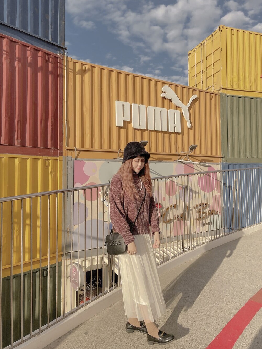 ブラック系のショルダーバッグ、ホワイト系のスカート、グレー系のニット/セーターを着用したレディースの冬コーディネートの2枚目の写真